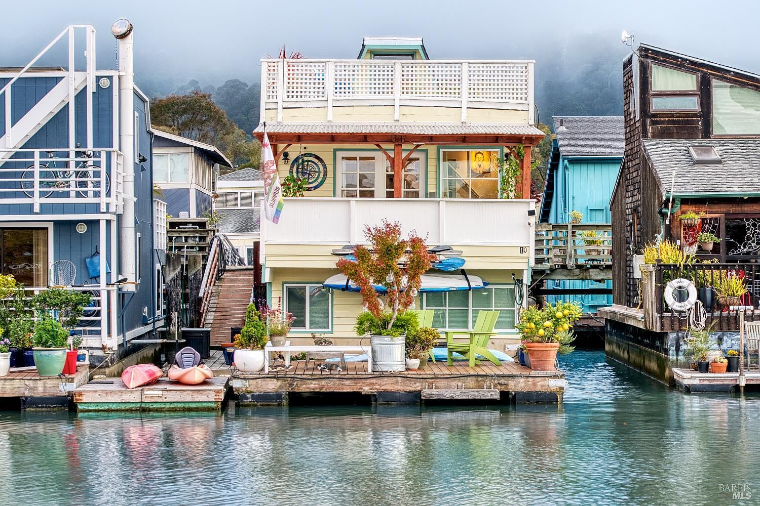 Twilight exterior view of the floating residence with copper roof, illuminated interior, and the bay reflecting evening light.